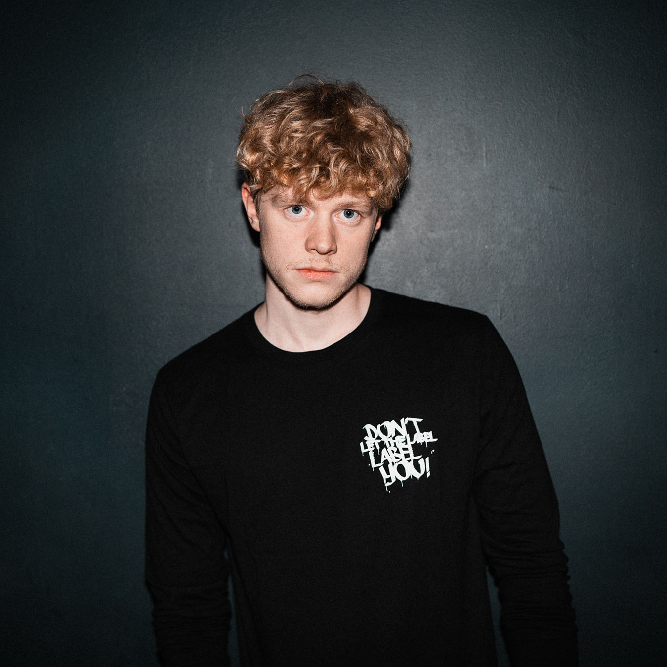 Blonder Mann in schwarzem Longsleeve der Hip Hop Plattform DLTLLY